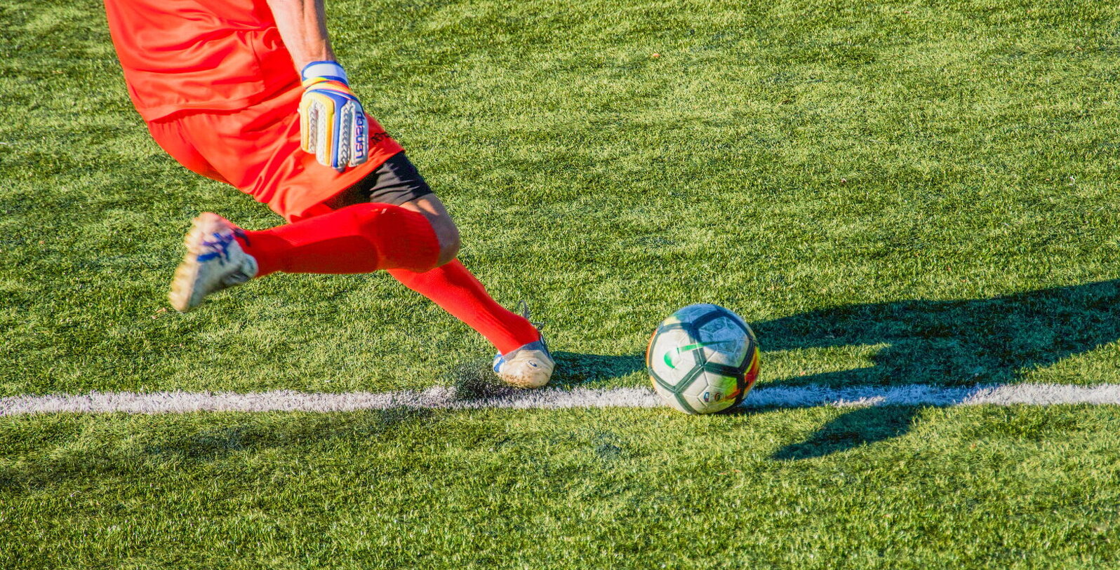 Bild på en fotbollsmålvakt som är på väg att göra en utspark av bollen.